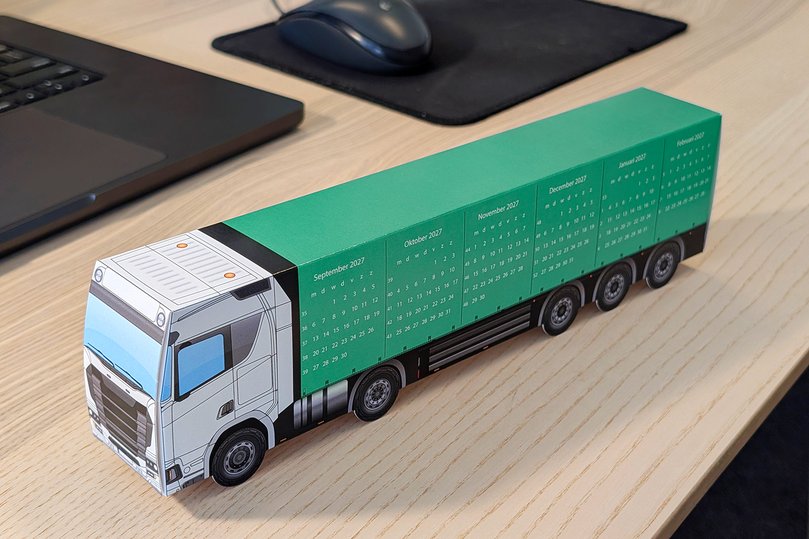 Green paper truck with a calendar on a desk